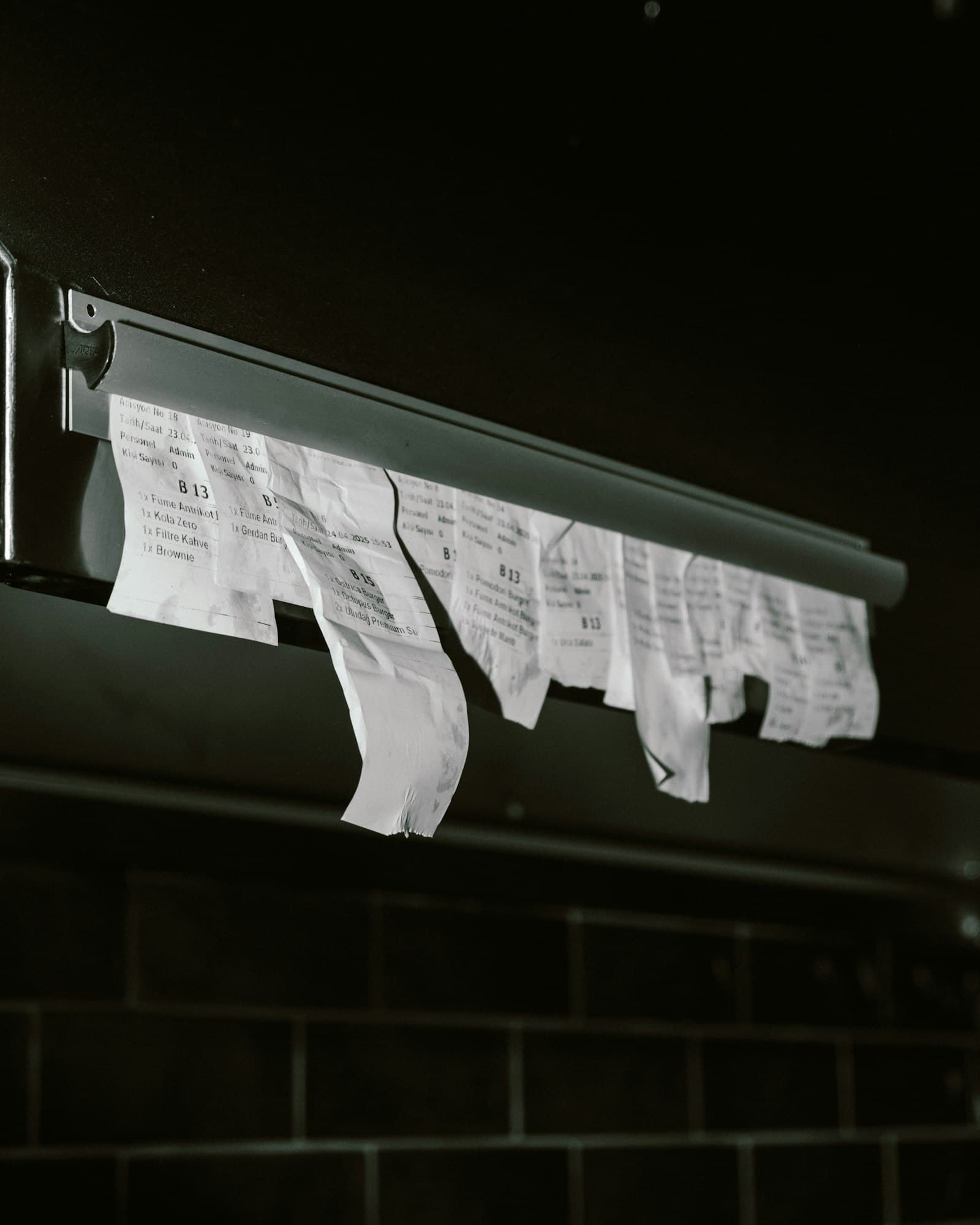 Torn paper receipts hanging from a kitchen order rail